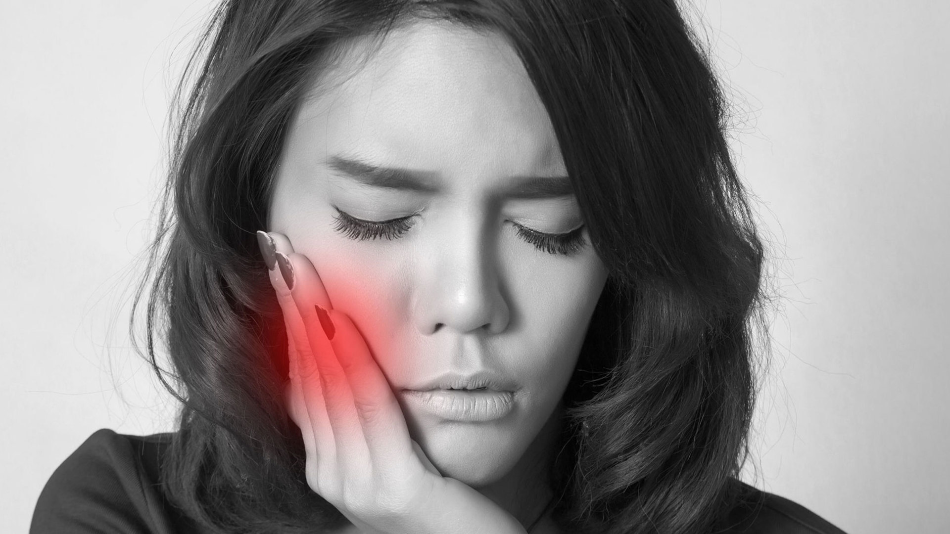 Person holding their cheek in pain from a tooth that is sensitive to hot and cold