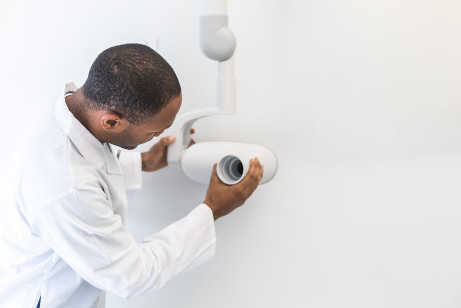 Dentist positioning a dental X-ray unit to evaluate bone before dental implant treatment